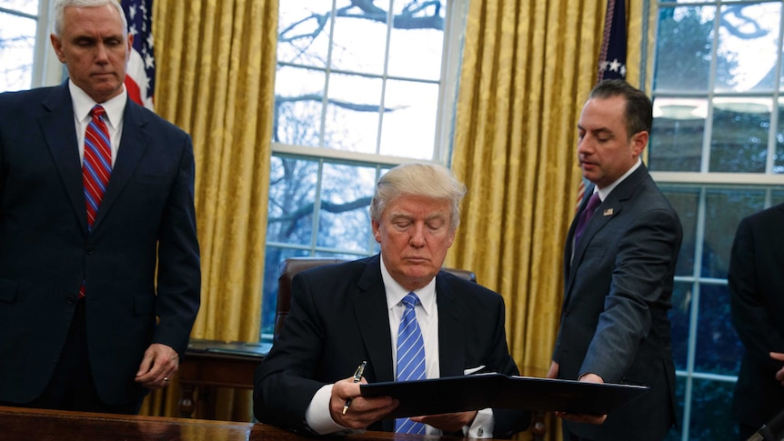 Donald Trump signs an executive order withdrawing the US from  the trade pact. (Photo: AP/Evan Vucci)