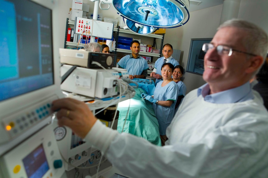 Professor Peter Macdonald with doctors and nursing staff in an operating theatre.