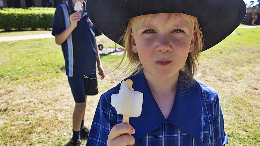 A young student eats an ice block