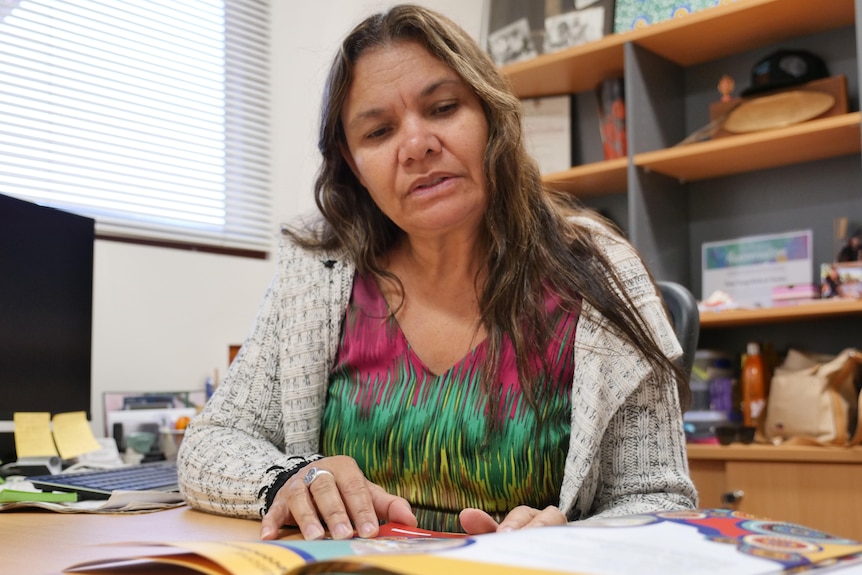 An Indigenous woman sits at her desk in an office