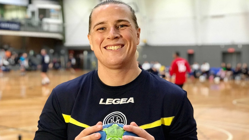 Hannah Mouncey smiling as she holds a handball in both hands.