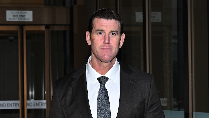 a man wearing a suit arriving at a court and looking at the camera