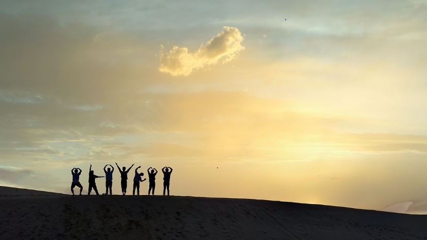Silloutte of a group of people standing against  sunrise on the top of a mountain 