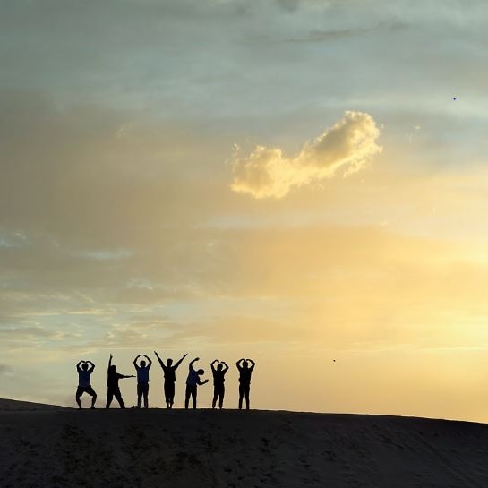 Silloutte of a group of people standing against  sunrise on the top of a mountain 