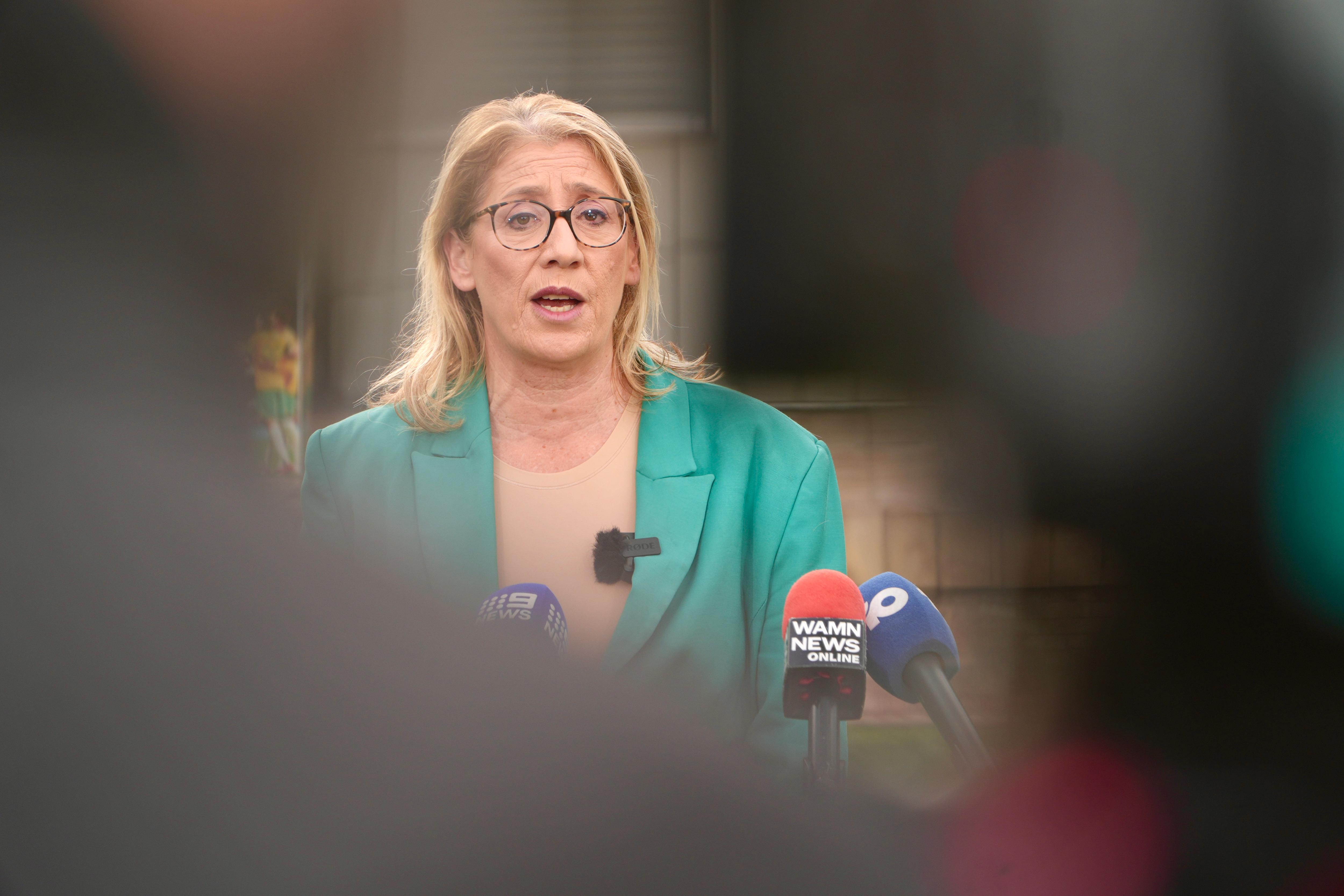 La viceprimera ministra de WA, Rita Saffioti, habla ante los micrófonos en una conferencia de prensa en el exterior. Lleva una chaqueta verde y un top beige.