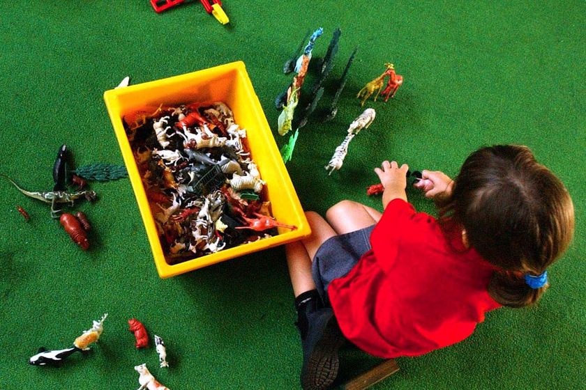 A child in a red top plays with a box of toys on the floor