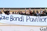 A group of people hold a banner reading 'save Bondi pavilion.'