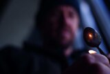 A blurred man holds a lighter under a spoon