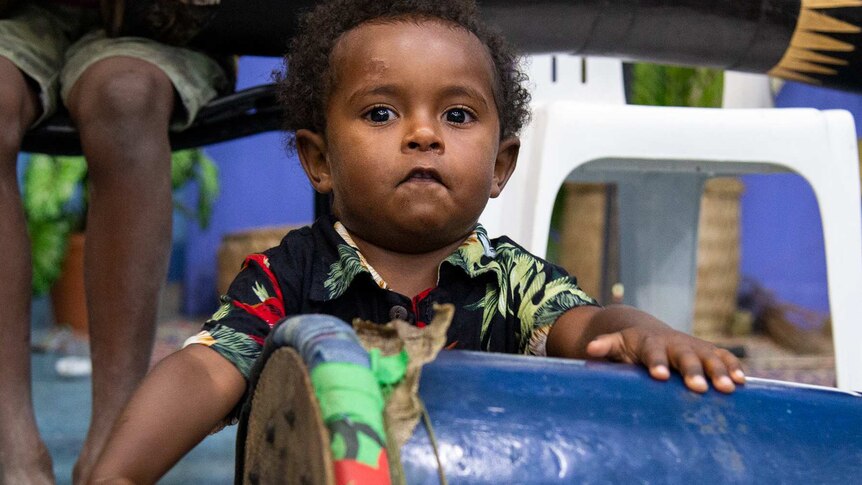 A small boy bangs on a drum.