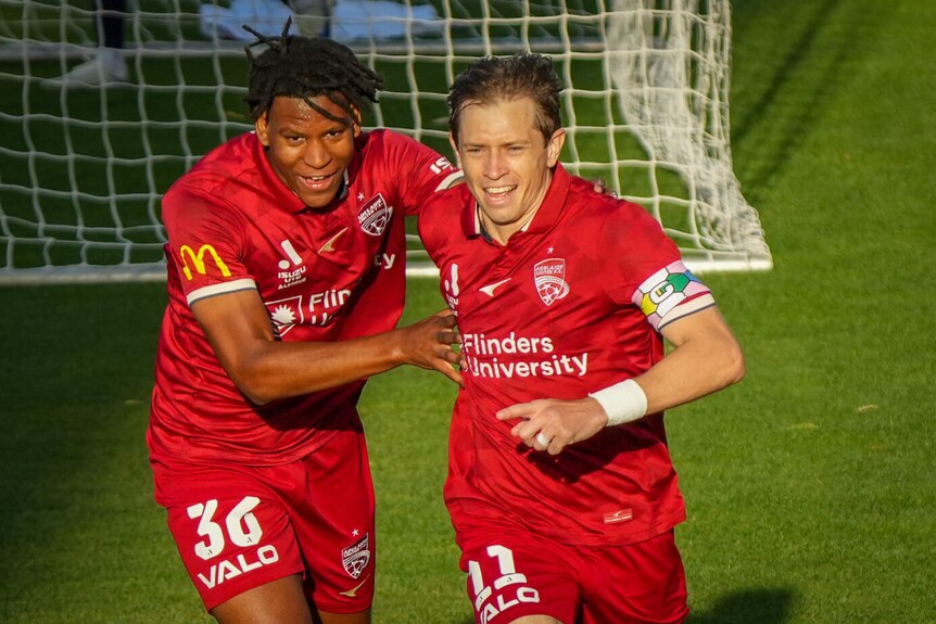 Two Adelaide United players celebrate.