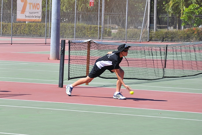 A girl and boy in uniform on the tennis courts in Darwin