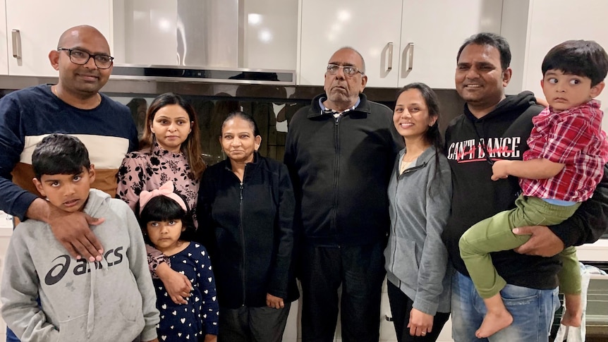 A large family poses for a photo in a modern-looking kitchen.