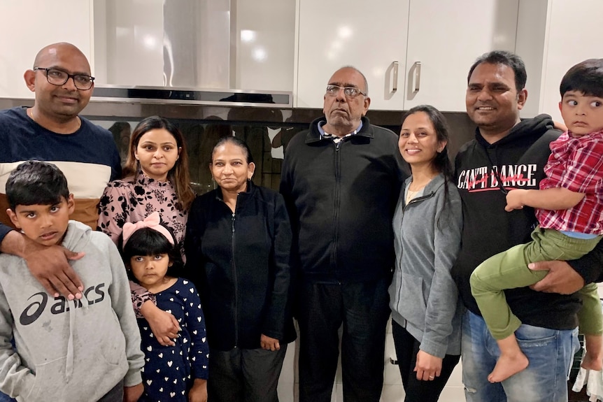 An indian family stands together for a photo in a modern kitchen
