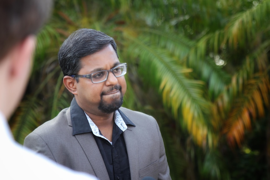 Abraham Thavaman addresses media with a pained expression