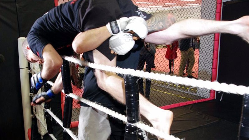 A mixed martial arts fighter throws another over ropes at a Perth boxing ring.