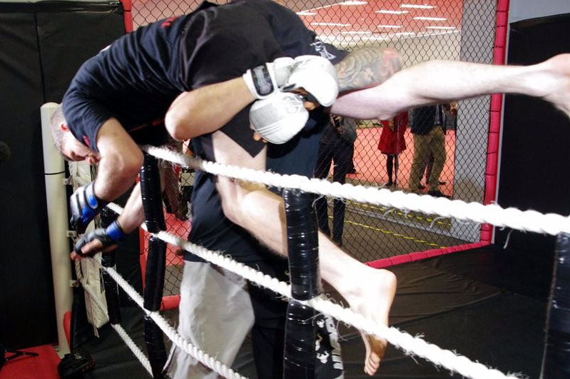 A mixed martial arts fighter throws another over ropes at a Perth boxing ring.