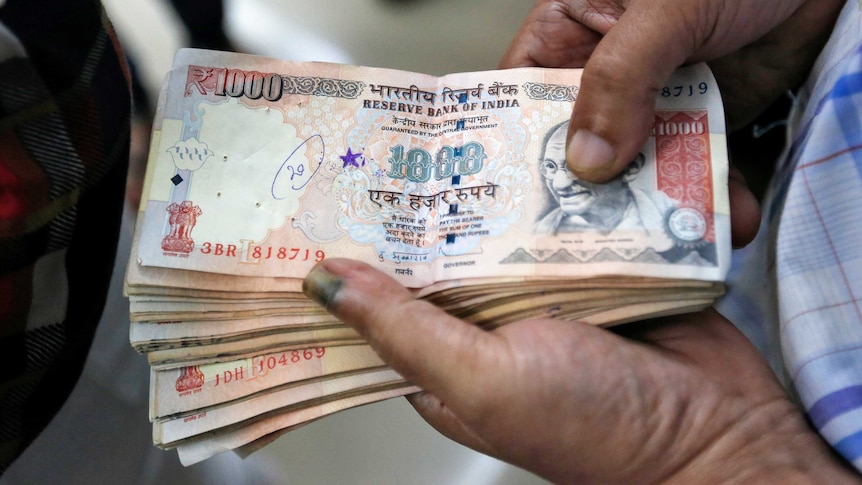 A customer waits to deposit 1000 Indian rupee banknotes.