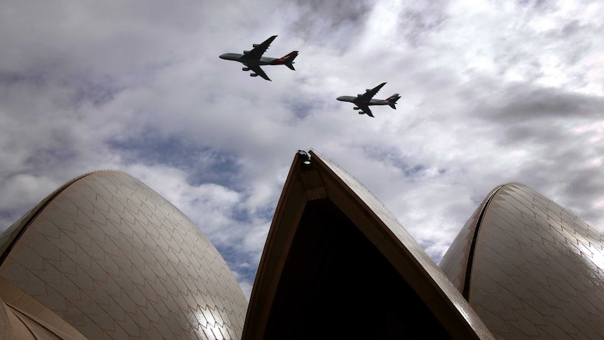 A Qantas Airways and an Emirates Airlines Airbus A380 fly above the Sydney Opera House.