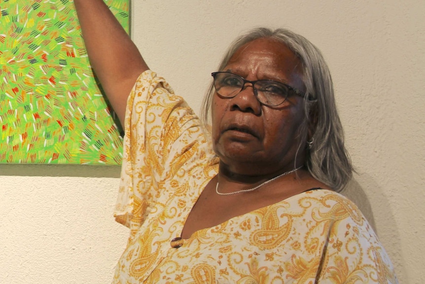 An Indigenous woman pointing to a painting