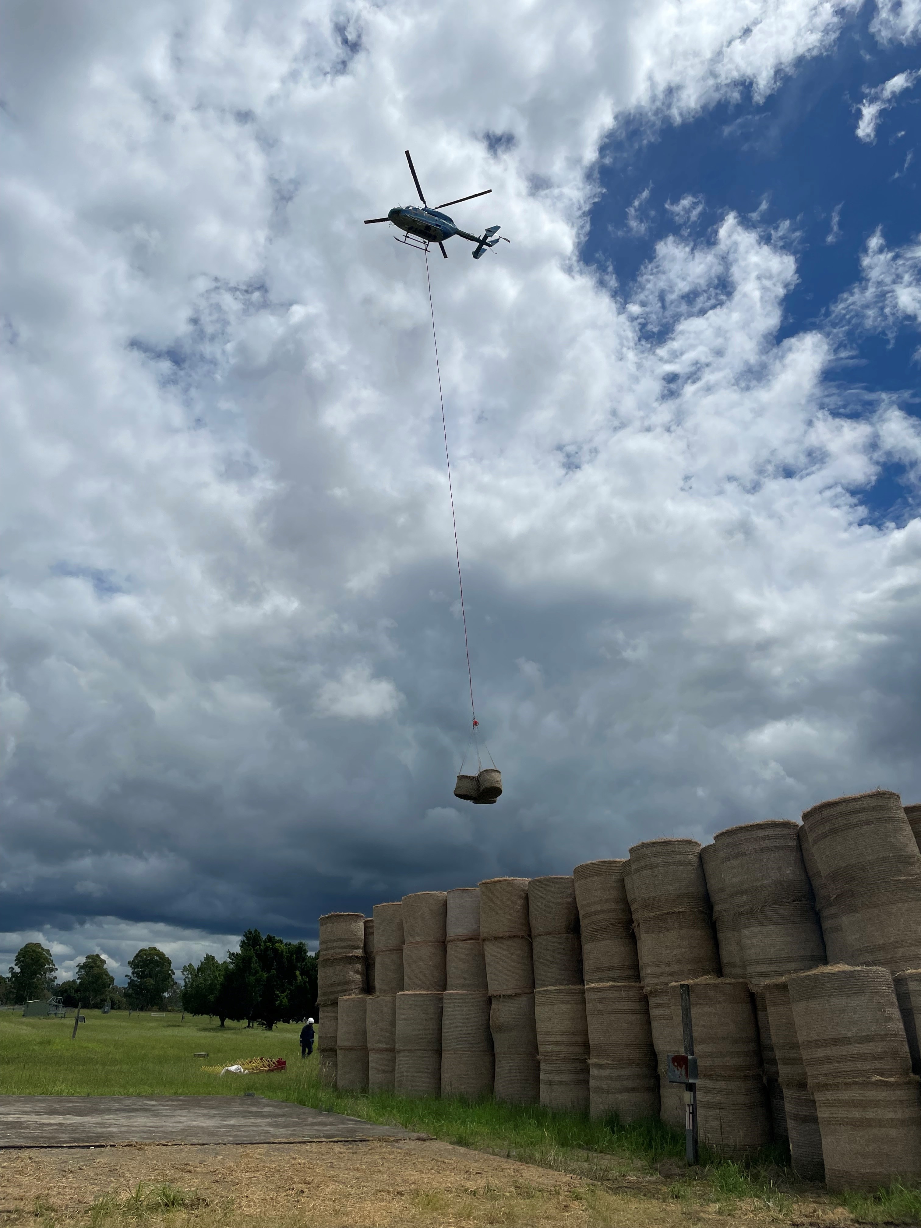 Helicopter dropping bales of hay on farm land