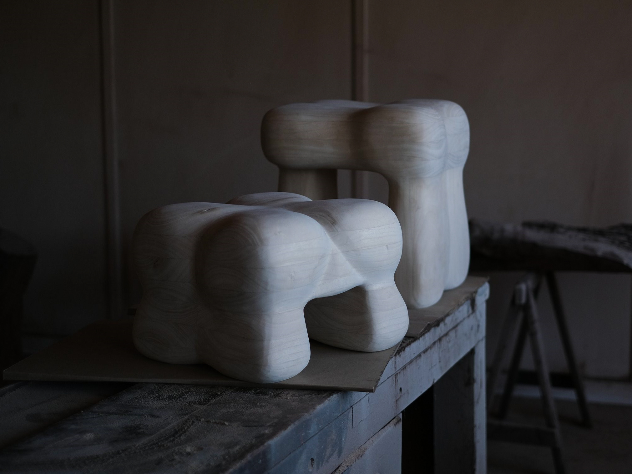 Completed wooden sculptures, in light coloured wood, that are light seats with 4 legs, and kind of look like butts