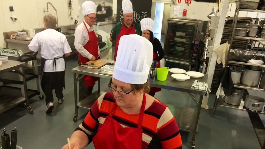 People take part in a City Mission cooking class in Launceston, learning how to make cheap meals.