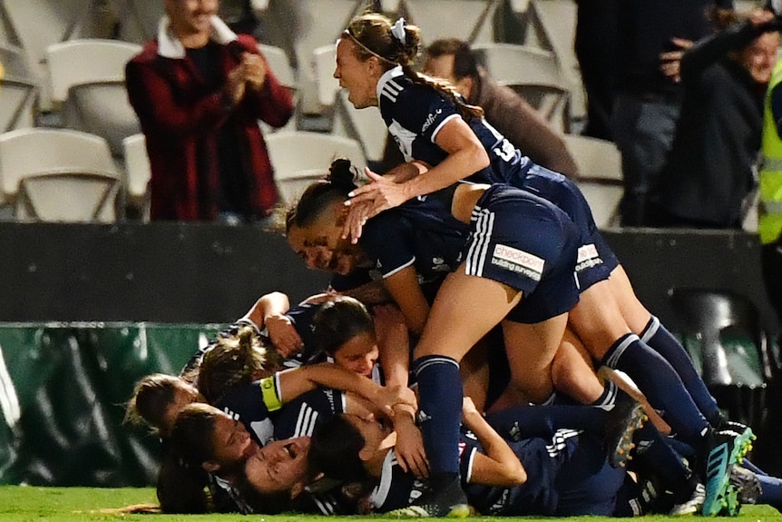 Melbourne Victory W-League players embrace as they celebrate the winning goal in the grand final.