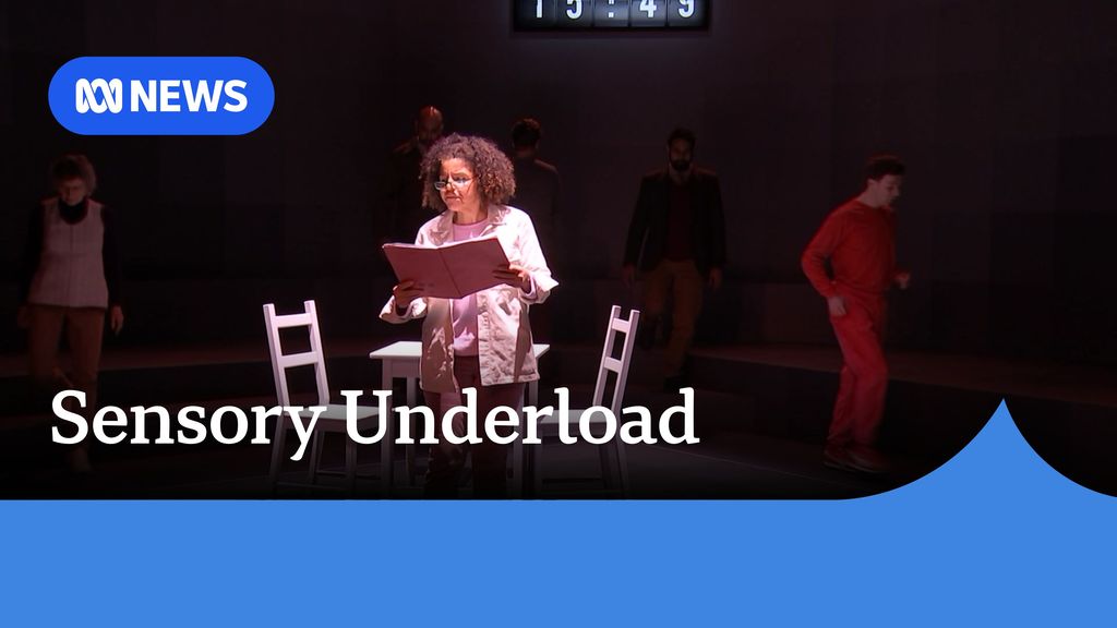 Sensory Underload: A woman reads from a script on a stage.