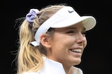 A female tennis player wearing a white hat cries