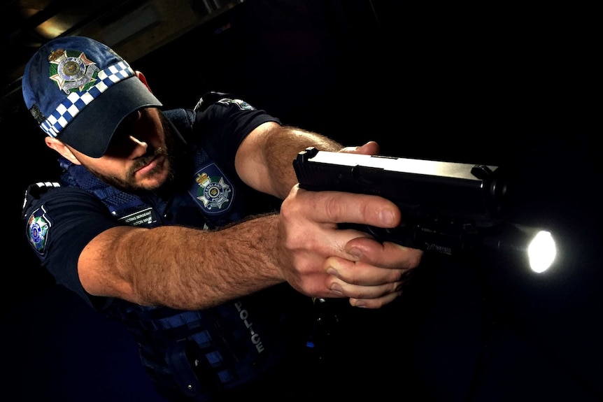 A Queensland police officer demonstrates the use of a weapon-mounted light in a dark environment