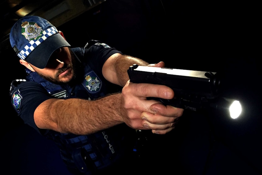 Queensland police officer Clinton Mair demonstrates weapon-mounted light