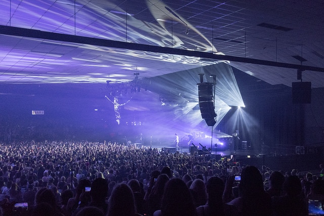 The interior of Festival Hall in Melbourne as strobe lights illuminate a crowd of people.