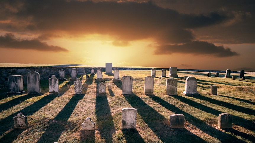 A cemetery with tombstones illuminated by the setting sun