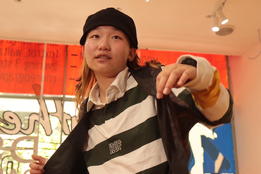  A Chinese girl lifts her vest with her fingertips while dancing