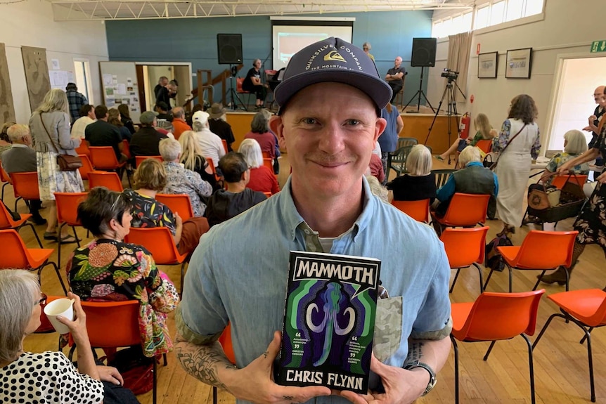 Chris Flynn holding copy of his book Mammoth at a regional writing festival.