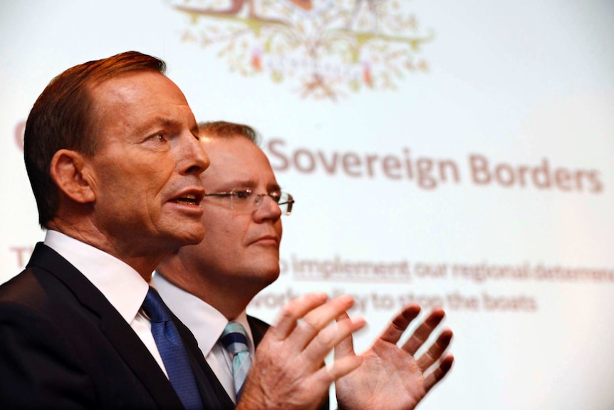 Tony Abbott speaks next to Scott Morrison in front of an Operation Sovereign Borders poster