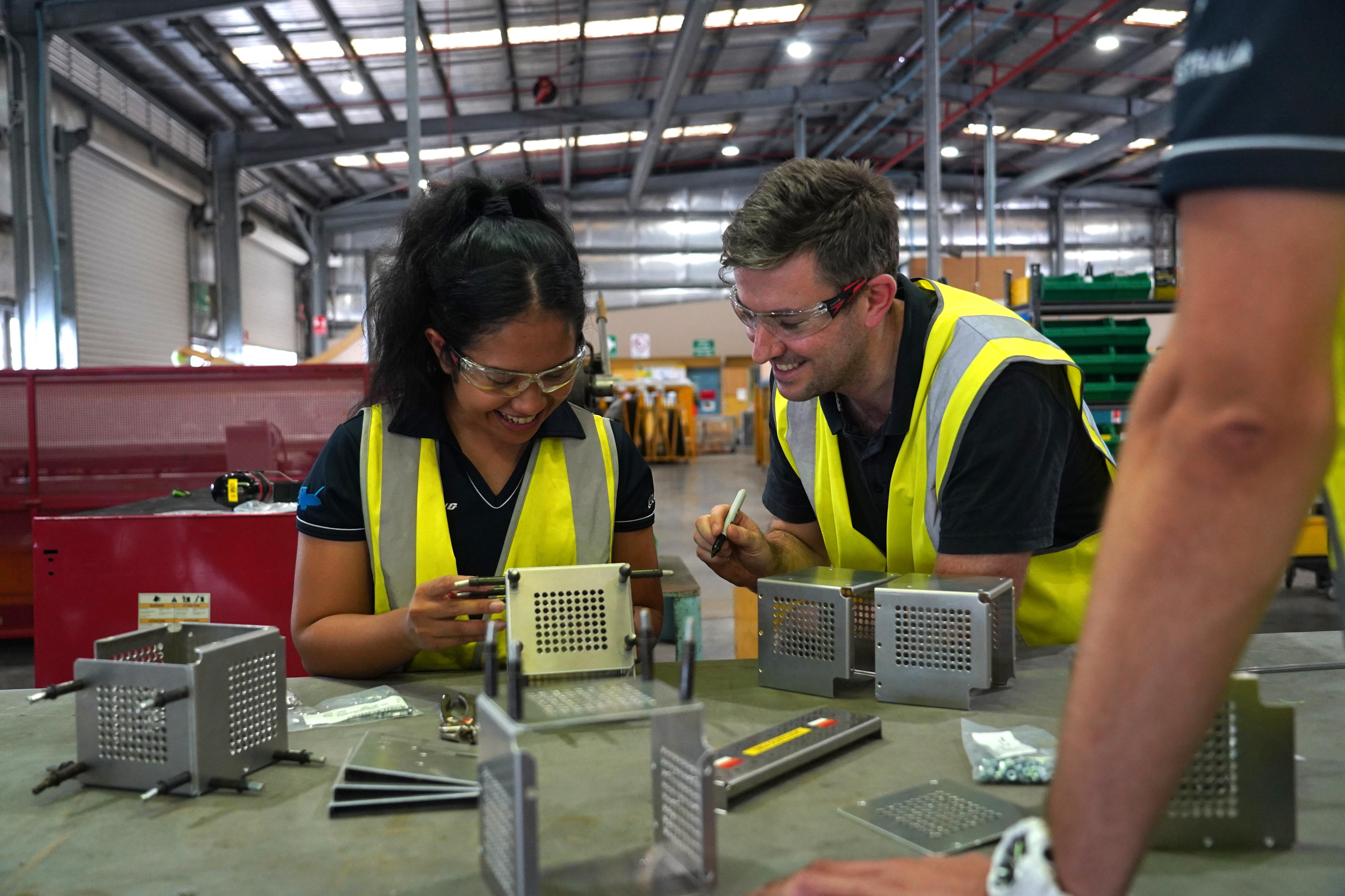 Woman and man standing around table fixing aircraft equipment