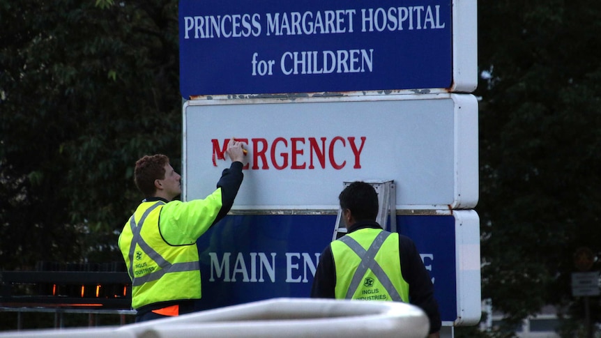 Two men in hi-vis clothing take down an emergency department decal on a Princess Margaret Hospital sign.