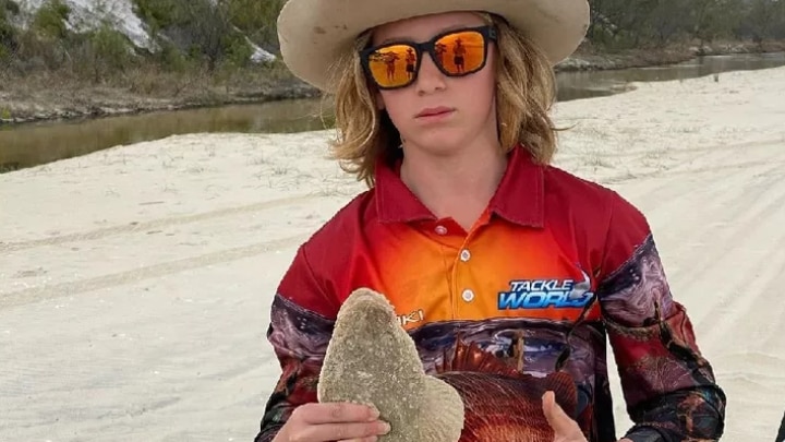 A boy in a red shirt holding a fish.