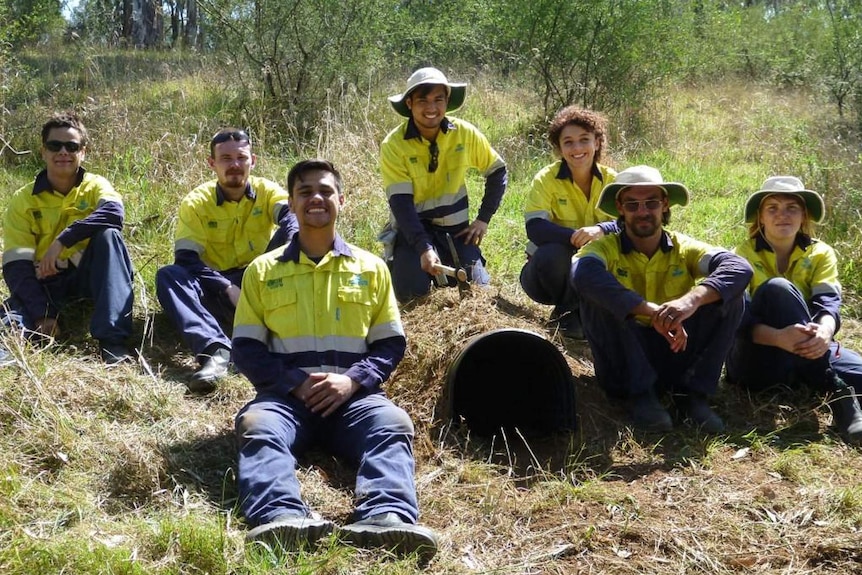 A group of volunteers posing with an artificial wombat burrow.