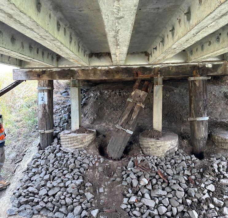 A wooden pillar is deteriorating below a bridge