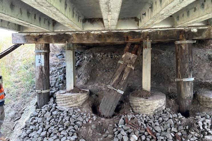 A wooden pillar is deteriorating below a bridge