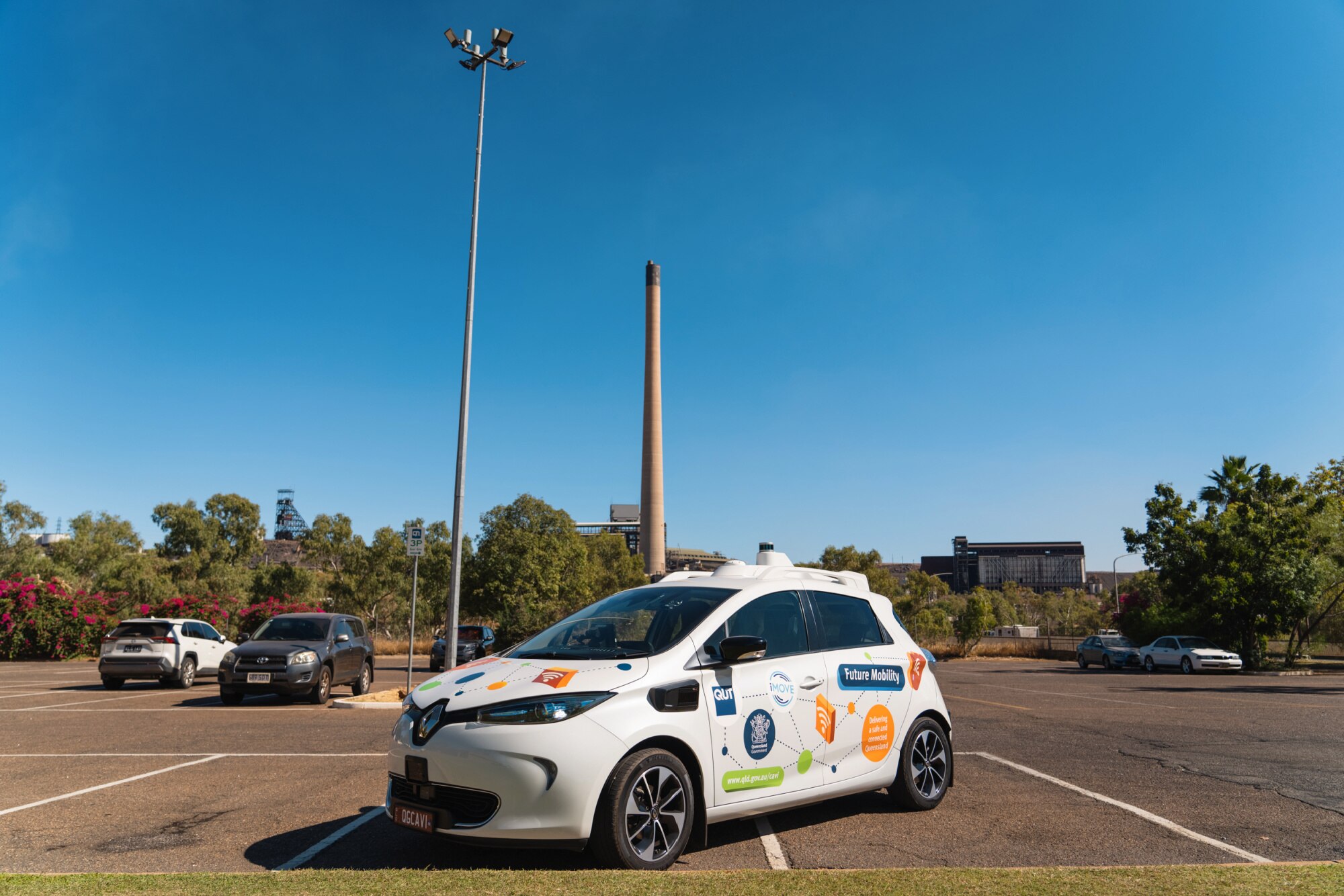 A small white car infront of a large mining stack