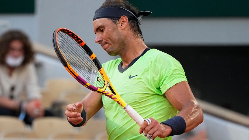 Rafael Nadal hits his racquet in frustration