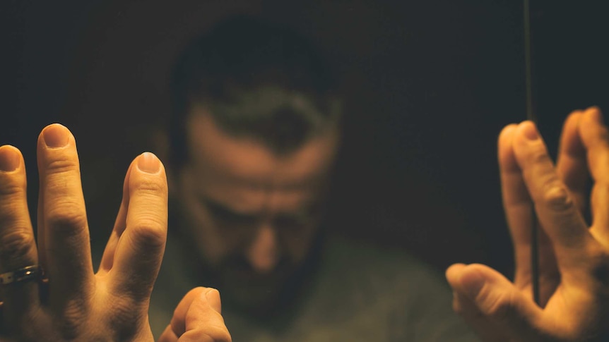 Upset man looking at himself in the mirror