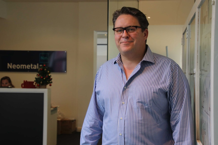 Neometals managing director Chris Reed stands and smiles with the company's reception area in the background.