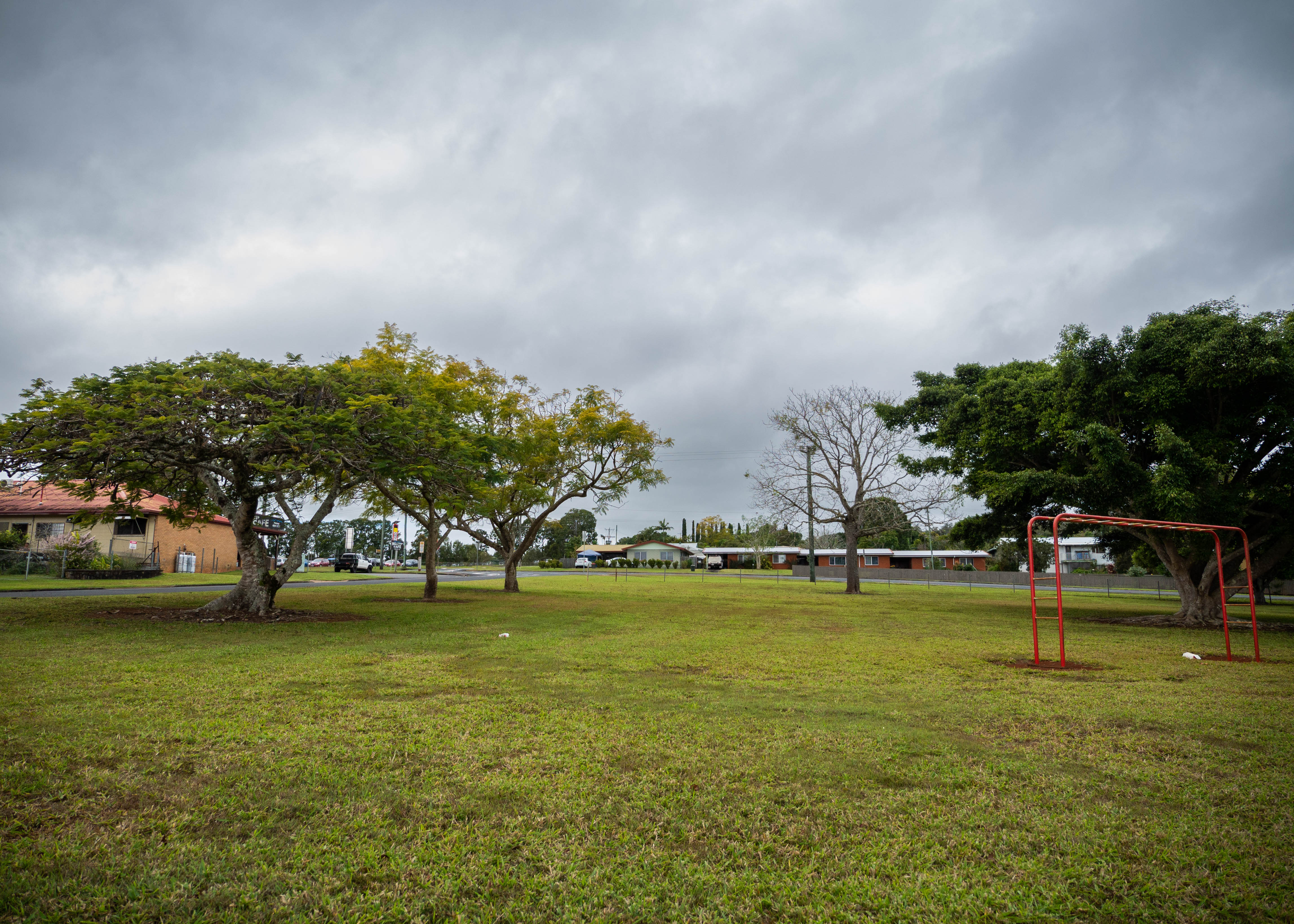 A wide shot of a park with trees and some play equipment on a gray day