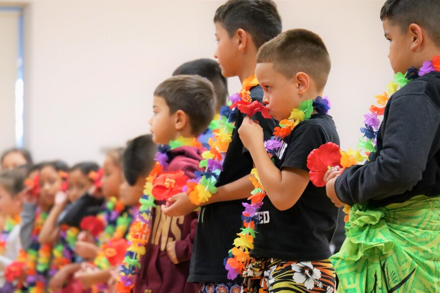 Young children with colourful lei's around their neck wearing traditional sarongs 
