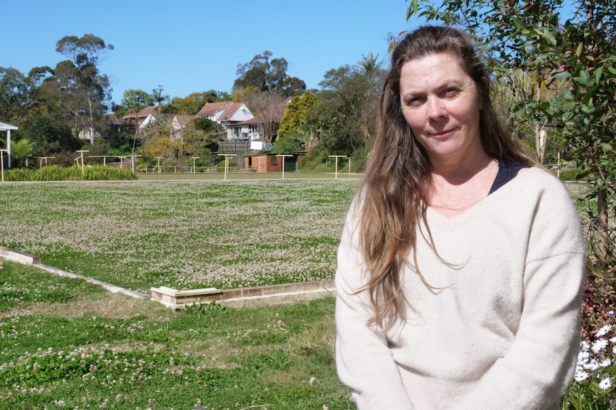 A woman in front of an overgrown disused lawn bowls field
