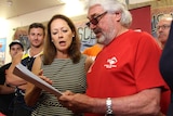 a man and woman holding a letter at press conference